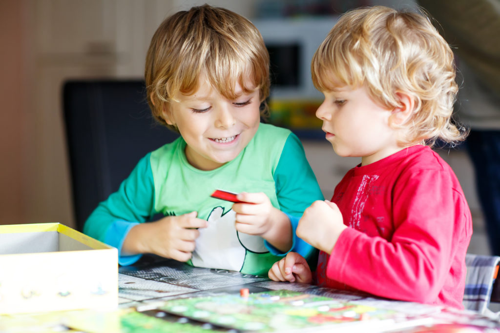 Two little blond kid boys playing together board game at home. Funny siblings having fun. Twins and best friends, toddlers learning interact, win and lose.