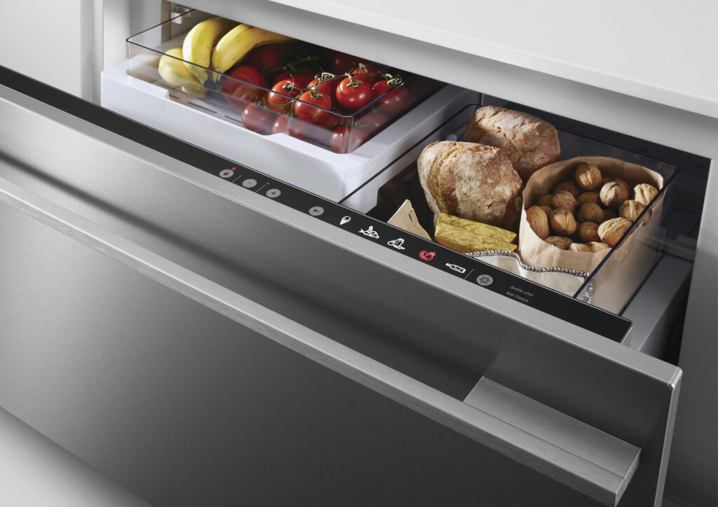 An open Fisher and Paykel drawer refrigerator, stocked with bread, butter, tomatoes, and bananas. 