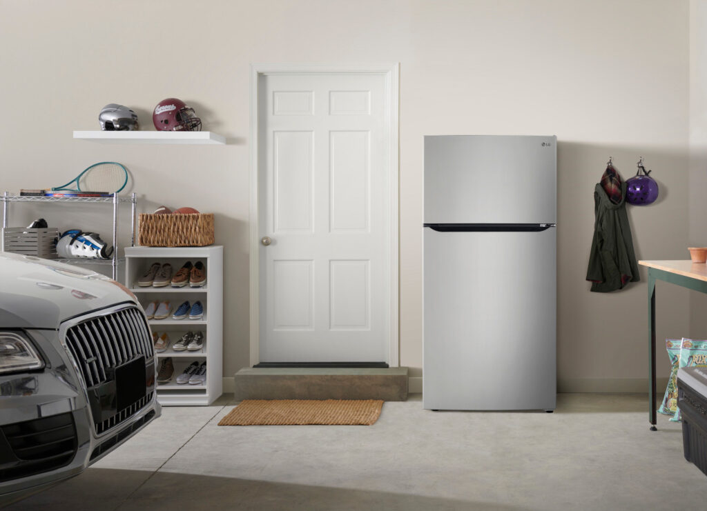 An LG stainless steel top freezer refrigerator in the garage. 