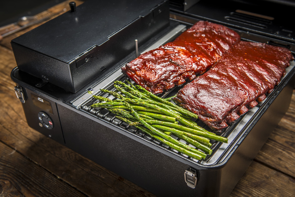 the Traeger Ranger Portable Grill with two racks of ribs and asparagus sitting on the grill.