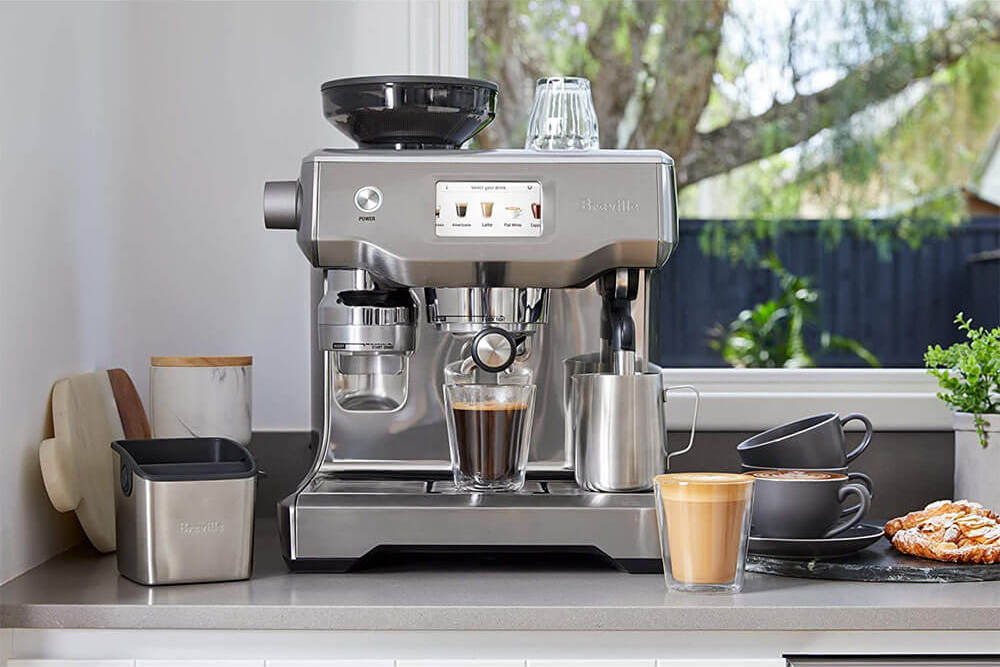 Breville home espresso maker with a milk steamer, touch screen, and espresso dispenser sitting on a countertop.
