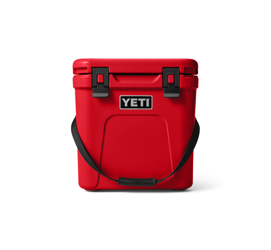 The red YETI Roadie 24 Hard Cooler on a white background, and the carrying strap hanging in front of the cooler.