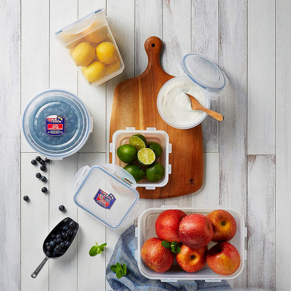 Lock & Lock food storage tupperware containers holding apples, limes, lemons, blueberries, and dip. Set on a wooden countertop.