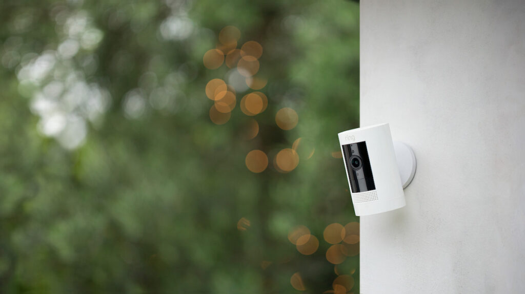 a Ring StickUp camera mounted outdoors on the side wall of a house.