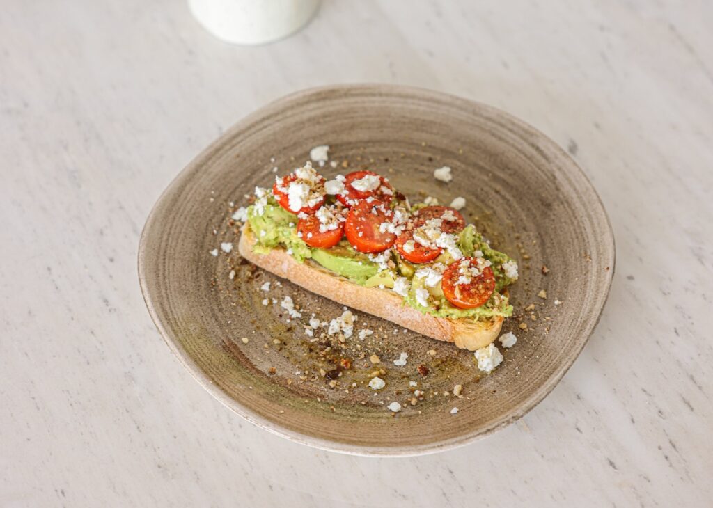 Slice of avocado toast with tomatoes and cheese.