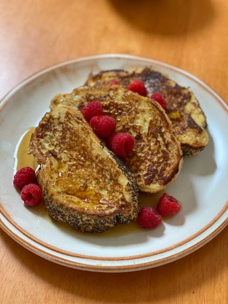 Brioche french toast served with maple syrup and raspberries.