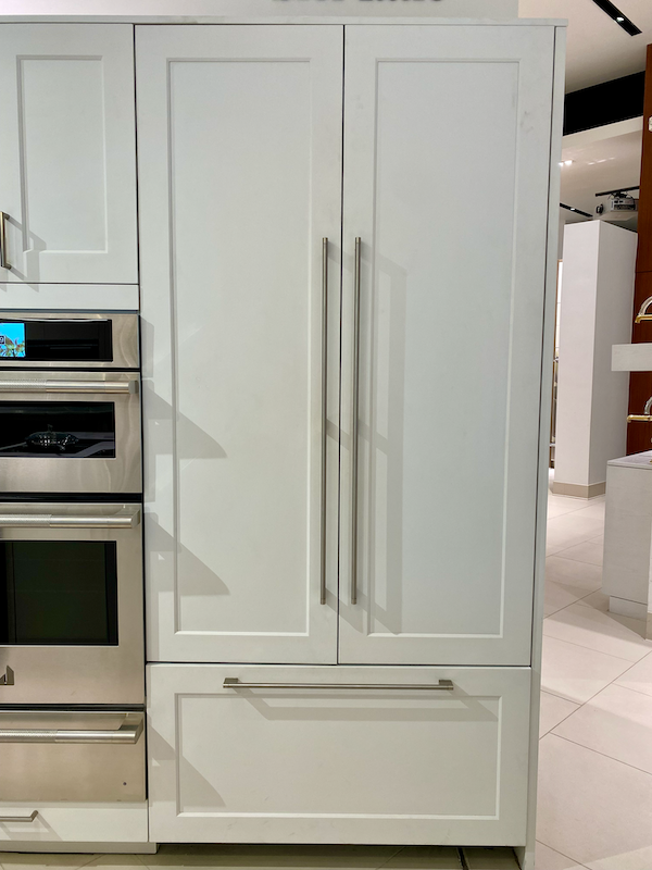 A JennAir French door refrigerator with bottom freezer drawer and mint-colored custom panels.