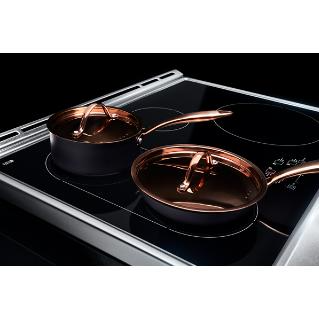 A JennAir induction cooktop with a copper saucepan and a copper frying pan sitting on the bridge cooking zone.