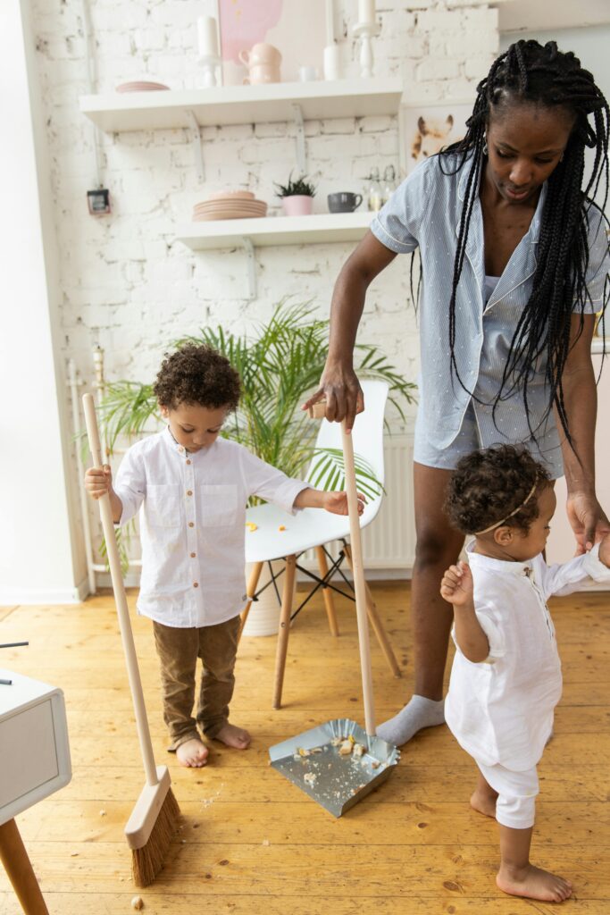 A mom and her kids sweeping the floors.