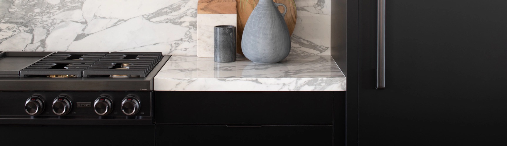 Black and graphite finish Dacor range and refrigerator in a black and white themed kitchen designed by Arash Hoss.